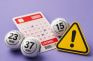 Bolas y boleto de lotería junto a señal de advertencia amarilla.